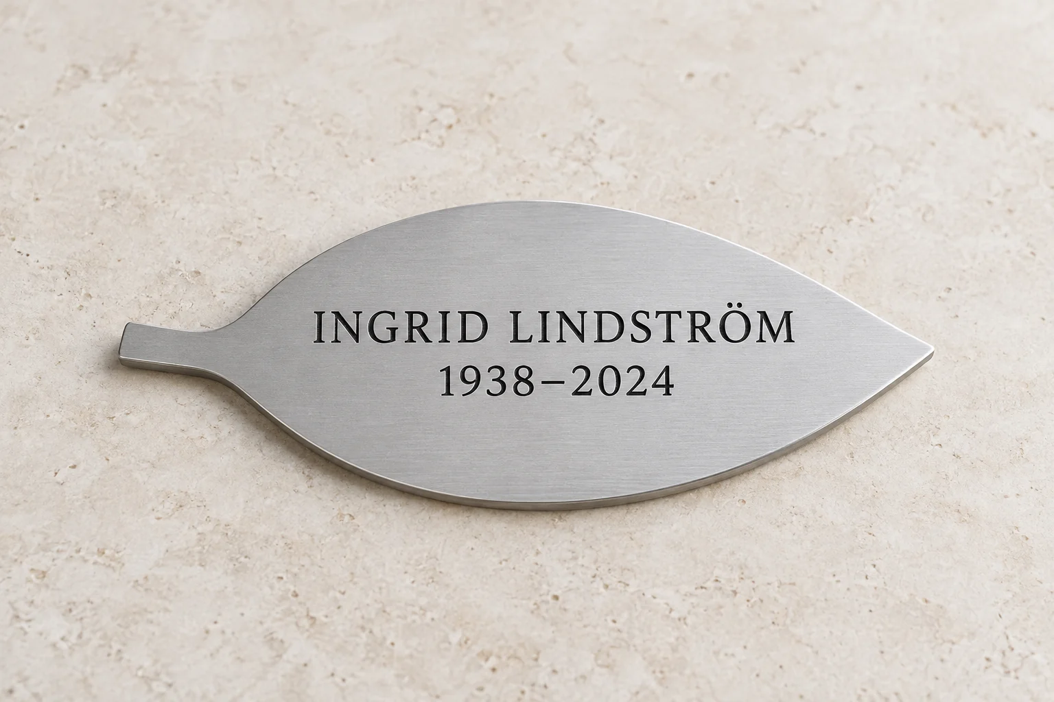 Illustrativ lövformad namnplatta i matt silverfärgad aluminium med exempeltext